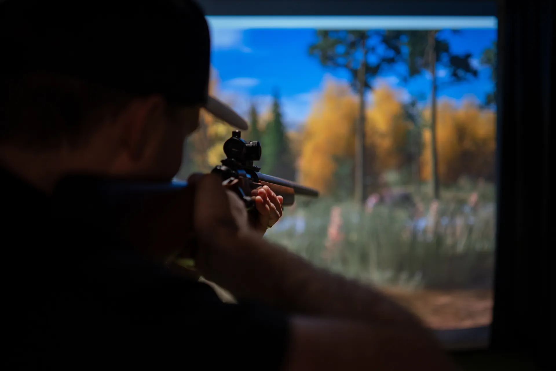 Skytt siktar mot en höstskog på simulatorns skärm